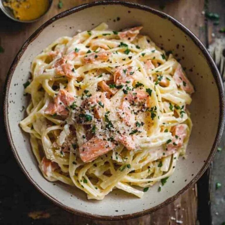 Pâtes au saumon fumé sans gluten avec une sauce crémeuse, parsemées de persil et de fromage râpé.