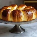 Brioche moelleuse dorée, joliment disposée sur un plat en métal, avec une décoration simple en arrière-plan.