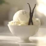 Glace à la vanille crémeuse servie dans un bol élégant, garnie de gousses de vanille et d'une légère poudre de vanille.