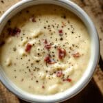 Bol de sauce carbonara maison crémeuse avec lardons et poivre noir sur une table en bois rustique