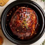 Jambon à la mijoteuse glacé avec épices et herbes, cuit à la perfection dans une cocotte.