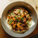 Bol de risotto crémeux aux champignons, garni de persil frais, avec un éclairage naturel mettant en valeur la texture du plat.
