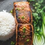 Deux filets de saumon glacé au miel et graines de sésame, servis avec du riz blanc et du bok choy.